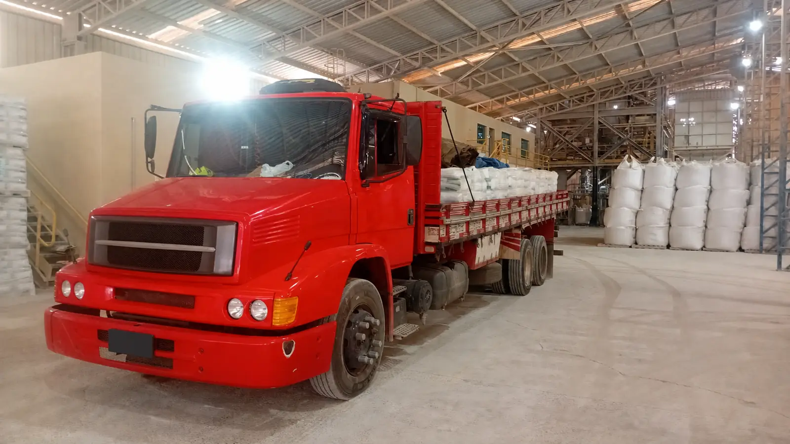 Matéria-prima ensacada sendo transportada dentro de instalação industrial