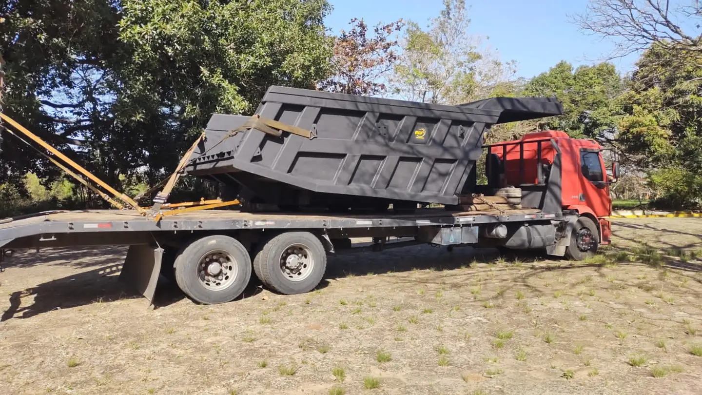 Caçamba industrial transportada em caminhão prancha