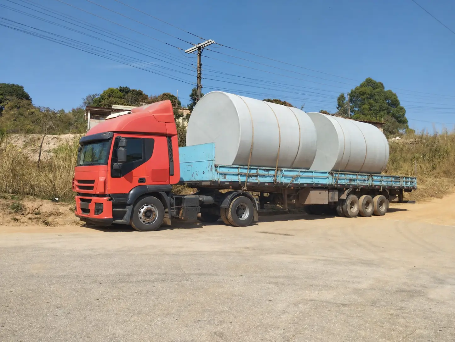 Dois tanques industriais transportados em carreta para obra de saneamento urbano