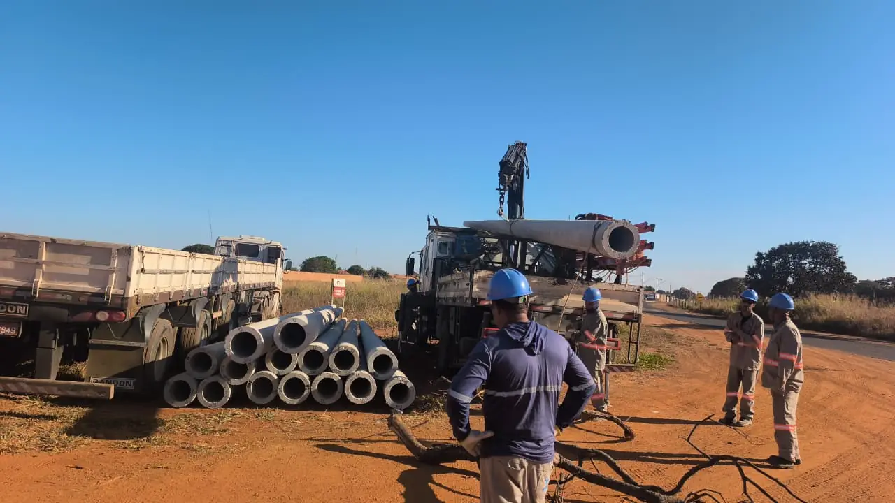 Equipe realizando movimentação de postes de concreto com caminhão munck